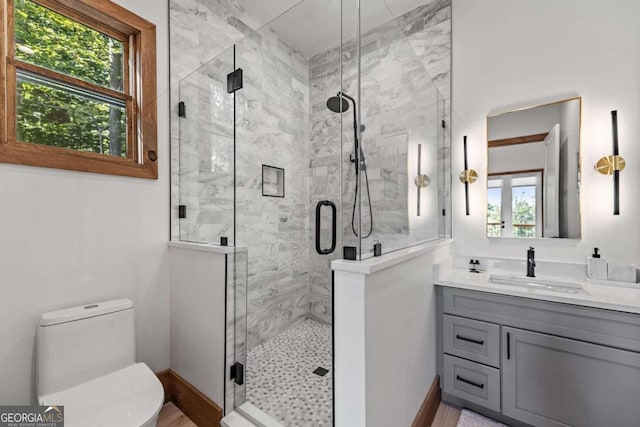 bathroom featuring a shower with shower door, toilet, plenty of natural light, and vanity