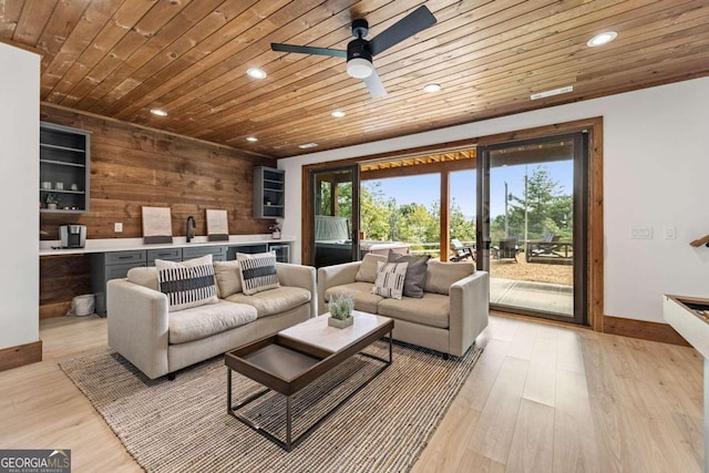 living room featuring sink, wood walls, ceiling fan, and light hardwood / wood-style floors