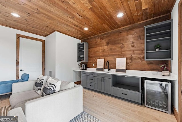 interior space featuring gray cabinets, light wood-type flooring, beverage cooler, sink, and wood ceiling