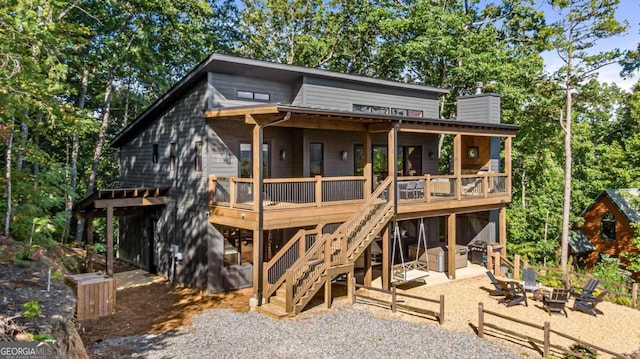 rear view of property featuring a fire pit, a patio area, and a deck