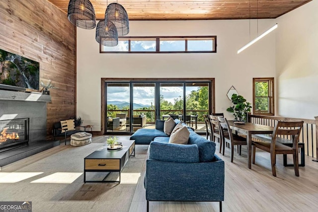 living room with a high ceiling, wood ceiling, hardwood / wood-style flooring, and a fireplace