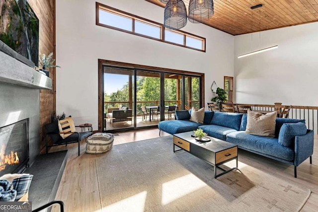 living room with a high ceiling, light wood-type flooring, wooden ceiling, and a fireplace