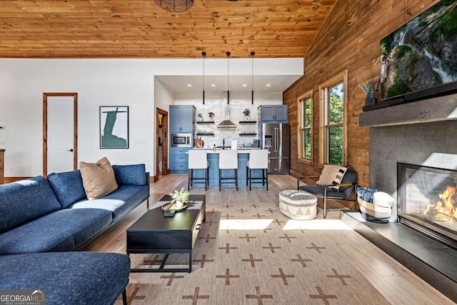 living room featuring wood ceiling, light wood-type flooring, high vaulted ceiling, and a fireplace