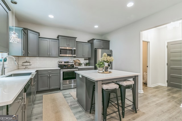 kitchen with light wood-type flooring, appliances with stainless steel finishes, a center island, and sink