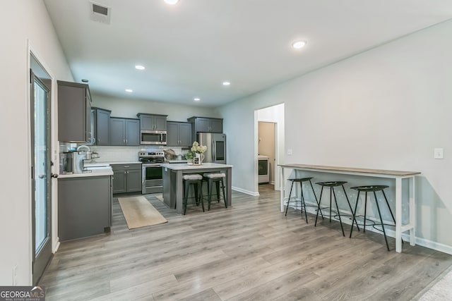 kitchen featuring a kitchen breakfast bar, light hardwood / wood-style flooring, a center island, stainless steel appliances, and plenty of natural light