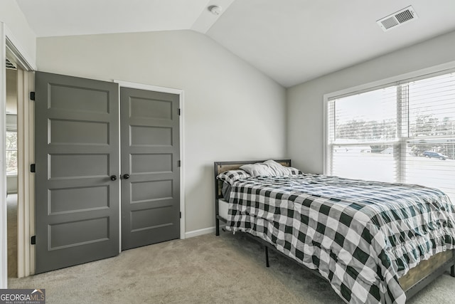 bedroom with multiple windows, vaulted ceiling, and light colored carpet