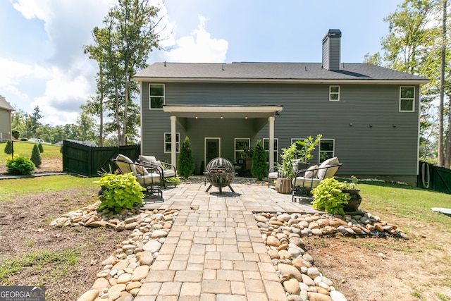 rear view of property with a fire pit, a patio area, and a lawn