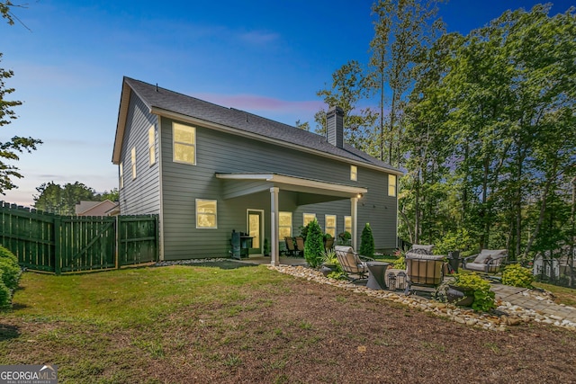 back house at dusk featuring a patio area and a yard