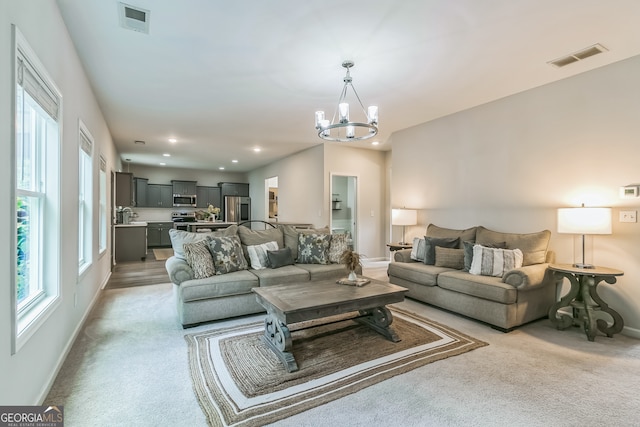 carpeted living room featuring an inviting chandelier