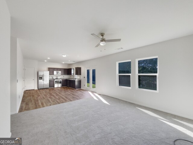 unfurnished living room with light wood-type flooring, ceiling fan, and sink