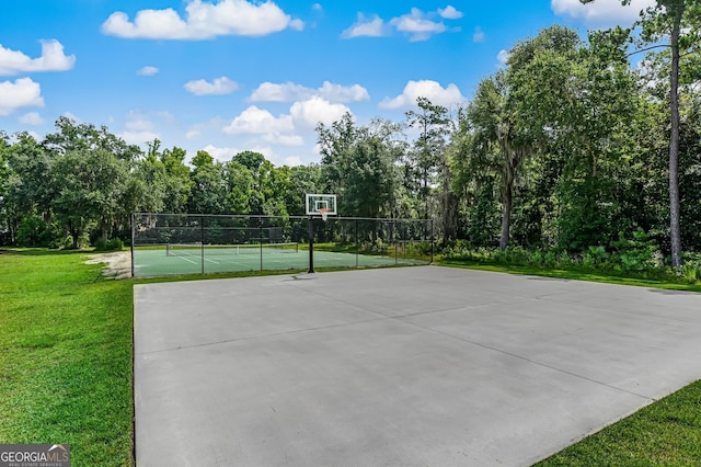 view of sport court featuring tennis court and a lawn