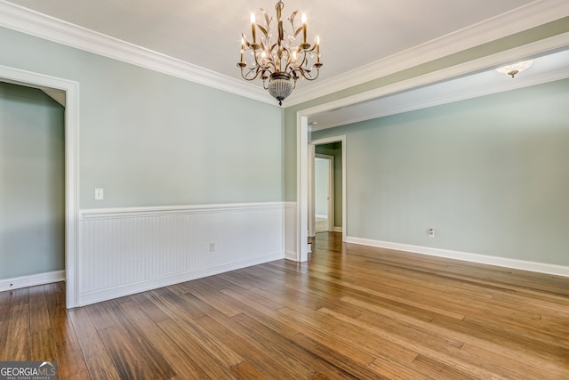 spare room with wood-type flooring, a chandelier, and crown molding