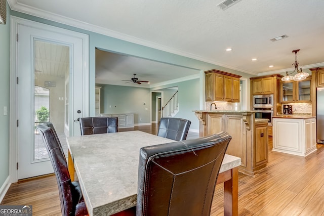 dining space featuring ornamental molding, ceiling fan with notable chandelier, and light hardwood / wood-style floors