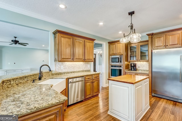 kitchen featuring ceiling fan with notable chandelier, light wood-type flooring, built in appliances, and pendant lighting