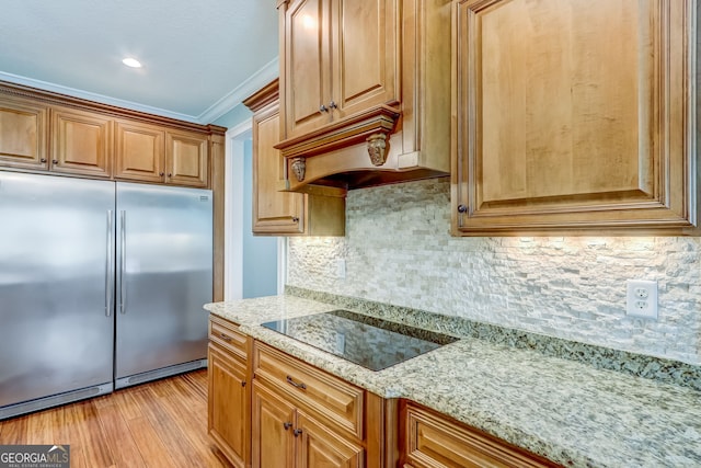 kitchen featuring stainless steel built in fridge, light hardwood / wood-style flooring, ornamental molding, black electric cooktop, and light stone counters