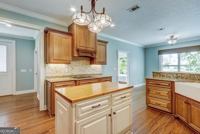 kitchen featuring crown molding, a chandelier, light hardwood / wood-style floors, butcher block counters, and a textured ceiling