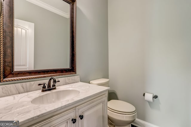 bathroom with crown molding, vanity, and toilet