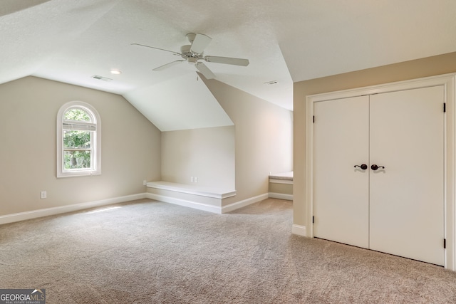 bonus room featuring lofted ceiling, ceiling fan, light carpet, and a textured ceiling