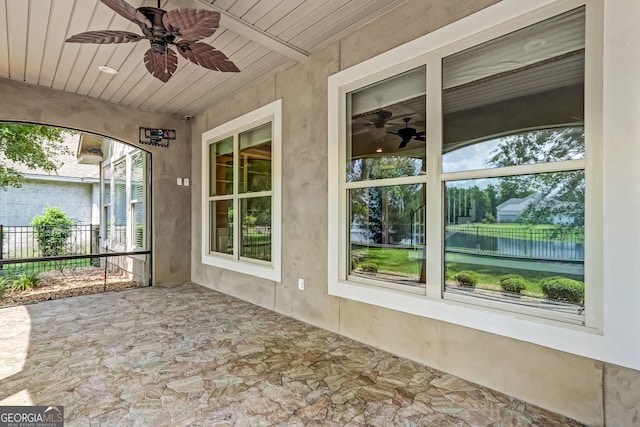 unfurnished sunroom featuring wooden ceiling, a healthy amount of sunlight, and ceiling fan