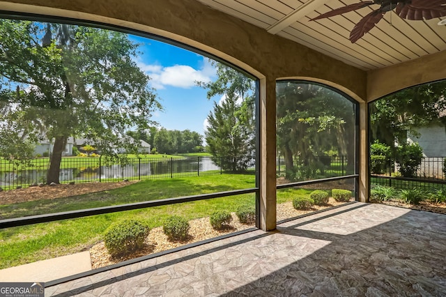 unfurnished sunroom featuring wood ceiling, ceiling fan, and a water view