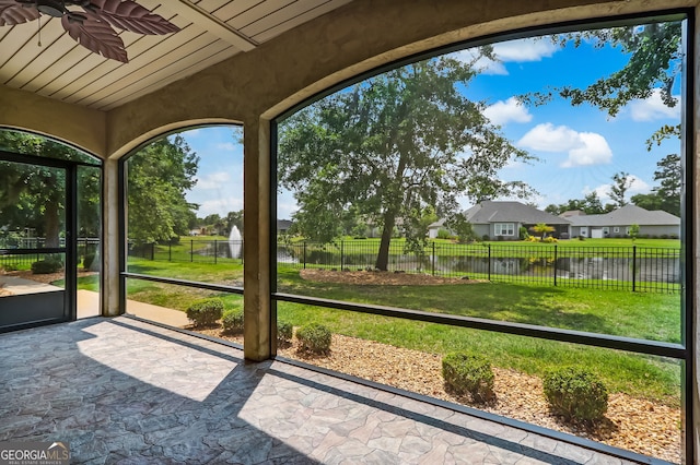 unfurnished sunroom featuring a water view and ceiling fan