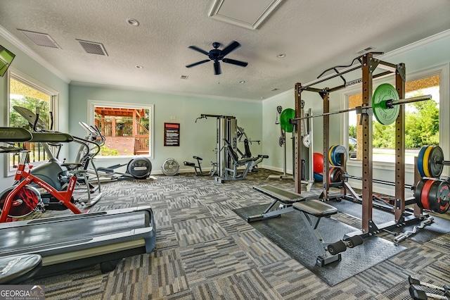 gym featuring a textured ceiling, ceiling fan, ornamental molding, and dark colored carpet