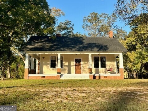 bungalow-style home featuring a front lawn and covered porch