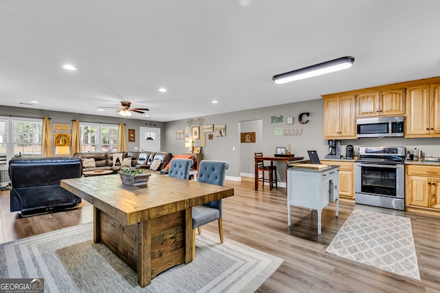 kitchen with a kitchen island, butcher block countertops, stainless steel appliances, ceiling fan, and light wood-type flooring