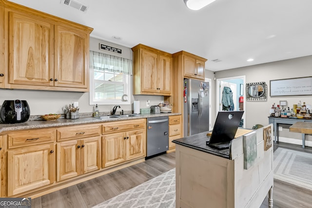 kitchen featuring light wood-type flooring, appliances with stainless steel finishes, light stone counters, and sink