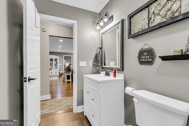 bathroom featuring wood-type flooring, toilet, and vanity