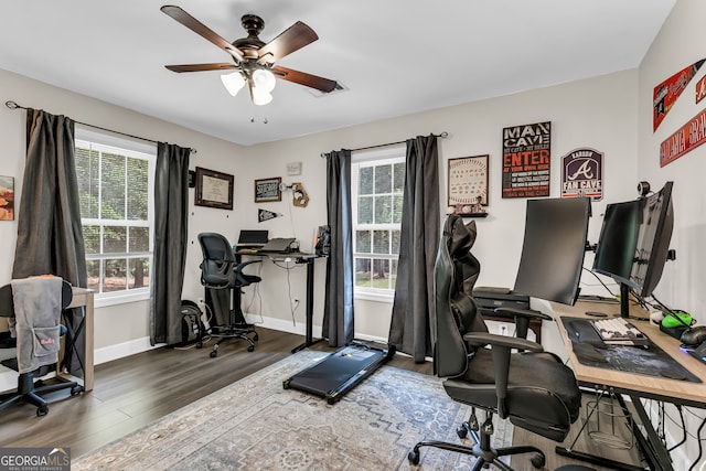 home office featuring plenty of natural light, ceiling fan, and dark hardwood / wood-style floors