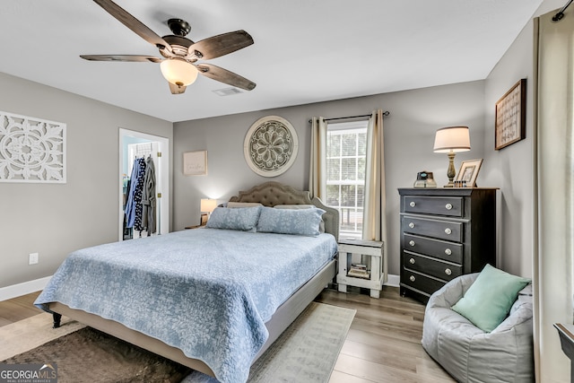 bedroom featuring hardwood / wood-style floors, ceiling fan, a spacious closet, and a closet