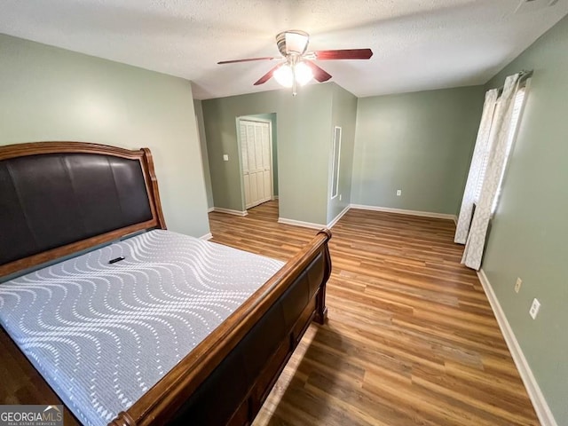 bedroom featuring hardwood / wood-style floors, ceiling fan, and a textured ceiling