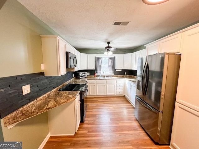 kitchen featuring light hardwood / wood-style flooring, appliances with stainless steel finishes, dark stone counters, and ceiling fan