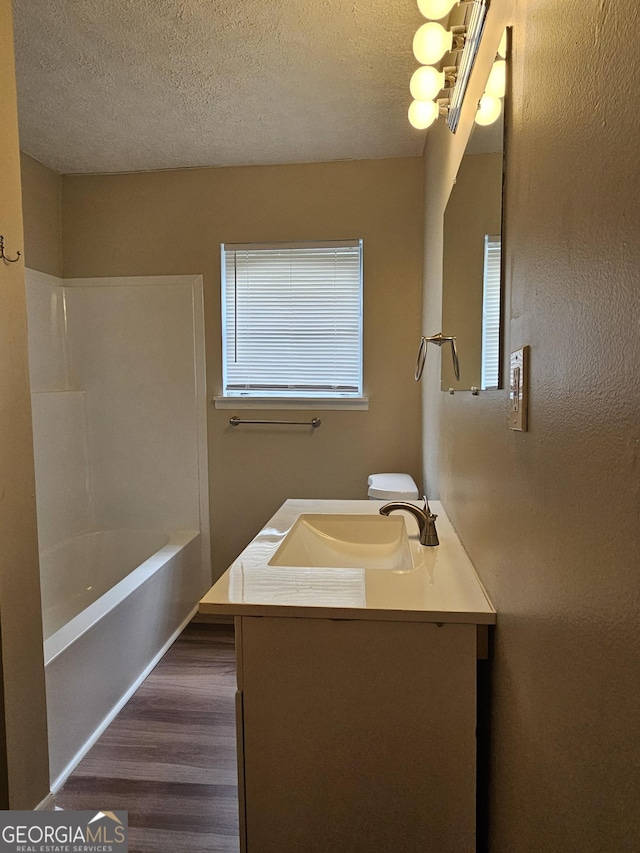 full bathroom with hardwood / wood-style flooring, vanity, shower / bathtub combination, and a textured ceiling