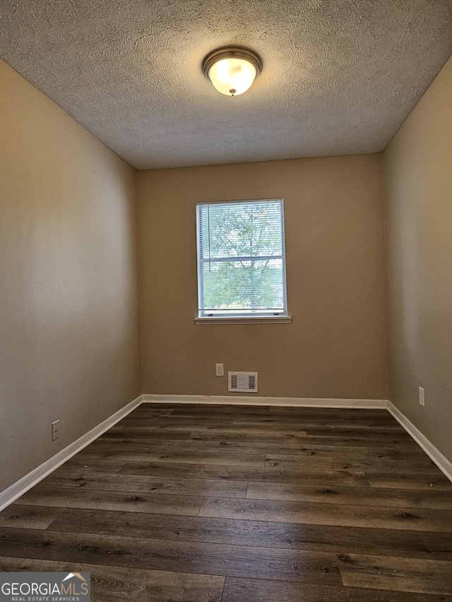 empty room featuring dark wood-type flooring and a textured ceiling