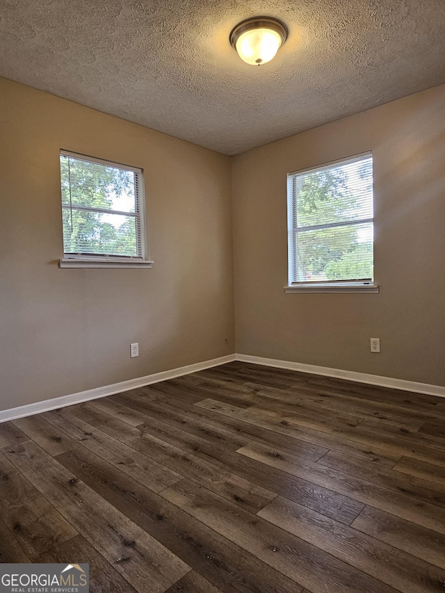 unfurnished room featuring dark hardwood / wood-style flooring, a textured ceiling, and a wealth of natural light