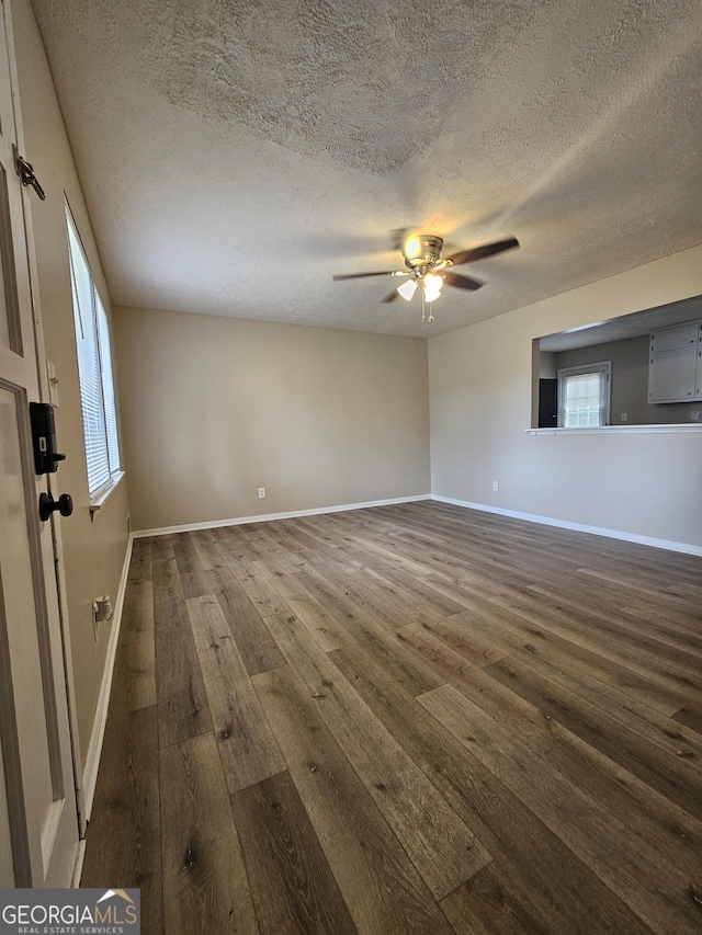 unfurnished room with a textured ceiling, dark hardwood / wood-style floors, and a wealth of natural light