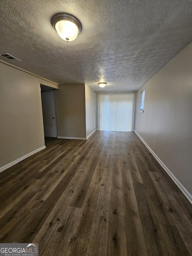 unfurnished room featuring dark hardwood / wood-style flooring and a textured ceiling