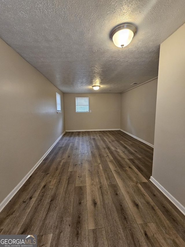 empty room with dark hardwood / wood-style flooring and a textured ceiling