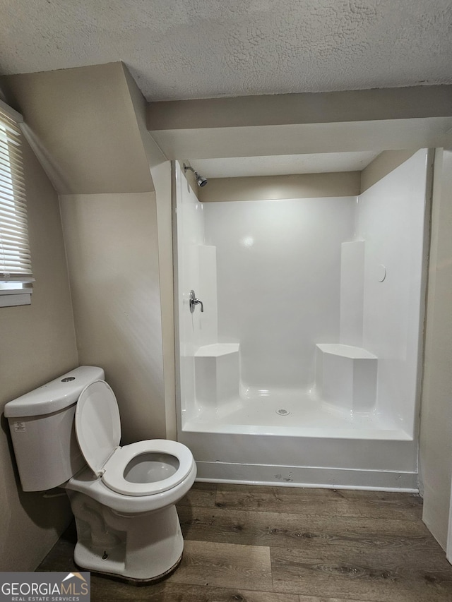 bathroom with a shower, toilet, a textured ceiling, and hardwood / wood-style flooring