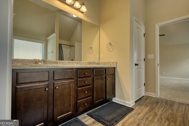 bathroom with hardwood / wood-style floors, vaulted ceiling, and vanity