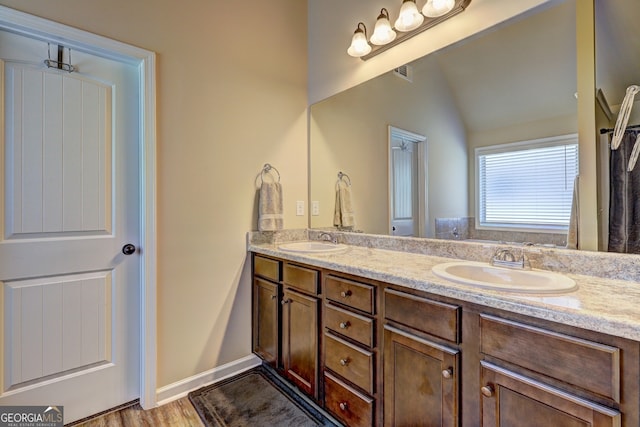 bathroom featuring hardwood / wood-style floors, vaulted ceiling, and vanity