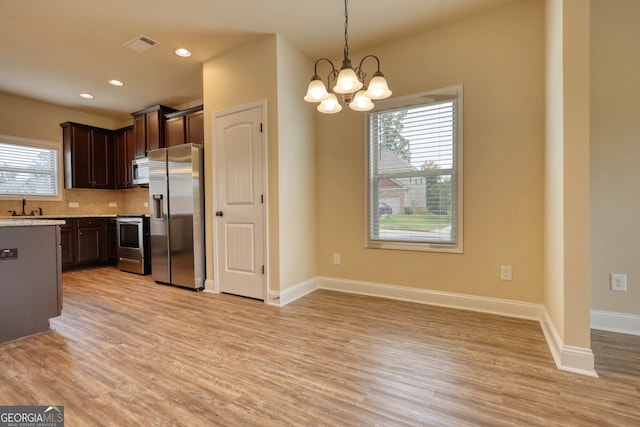 kitchen featuring hanging light fixtures, an inviting chandelier, stainless steel appliances, light hardwood / wood-style floors, and dark brown cabinetry