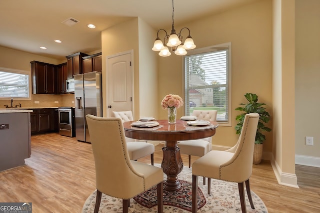 dining room featuring light wood-type flooring, plenty of natural light, and a chandelier