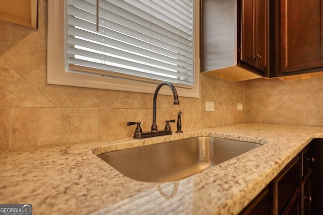 kitchen featuring light stone counters, sink, and backsplash