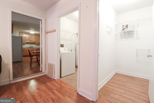 hall featuring washer / clothes dryer, light wood-type flooring, and sink