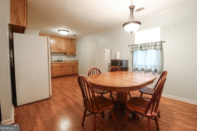 dining space featuring ornamental molding, sink, and light hardwood / wood-style floors