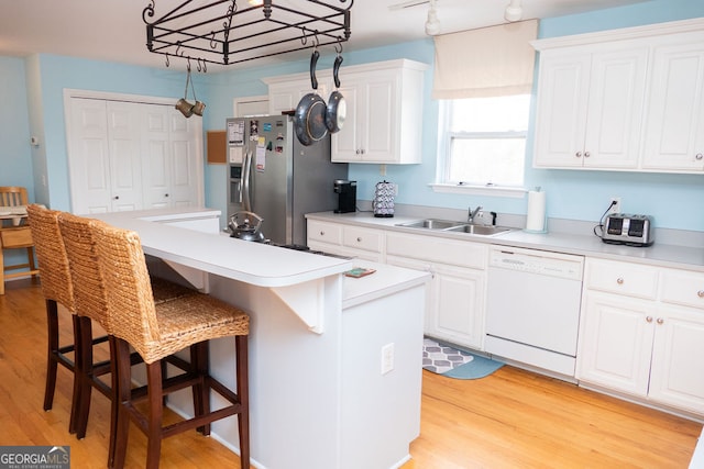 kitchen featuring white cabinets, white dishwasher, a center island, light hardwood / wood-style flooring, and sink