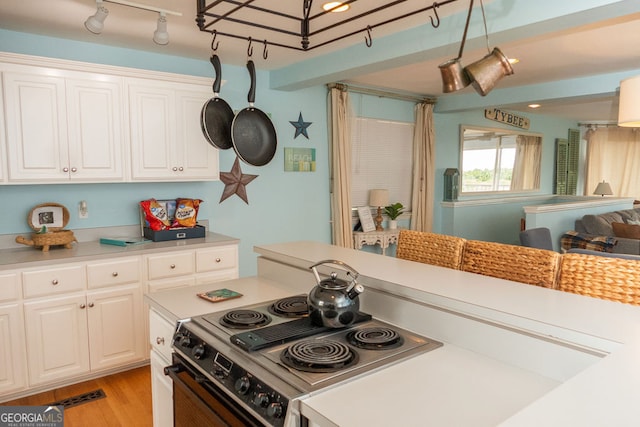 kitchen featuring light hardwood / wood-style floors, pendant lighting, range with electric stovetop, and white cabinets